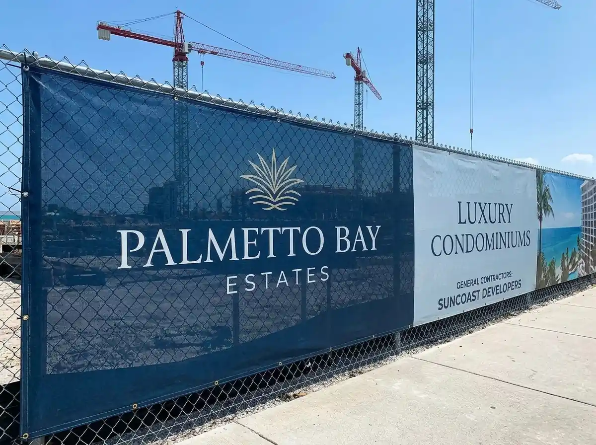 Printed fence banner announcing a residential development under construction